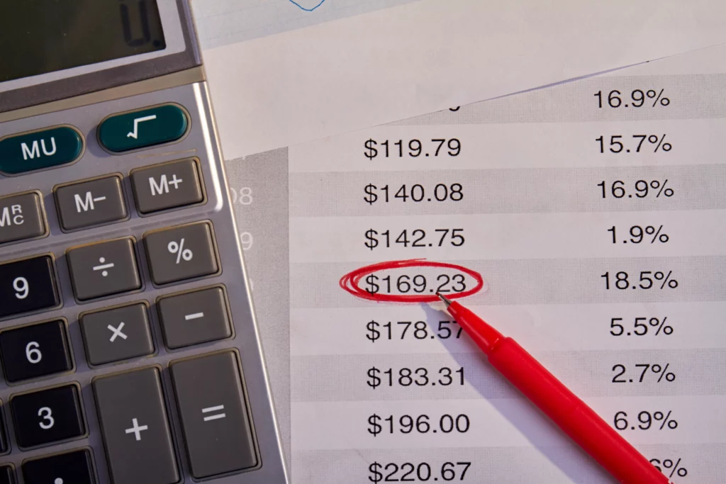 Calculator and red pen on financial document with $169.23 circled, representing rental payment reporting
